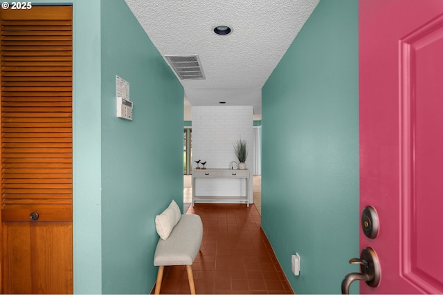 corridor with dark tile patterned floors, visible vents, and a textured ceiling