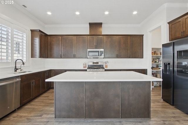 29169 NW King St, North Plains, OR 97133 - kitchen with crown molding, dark brown cabinetry, a kitchen island, a sink, and appliances with stainless steel finishes