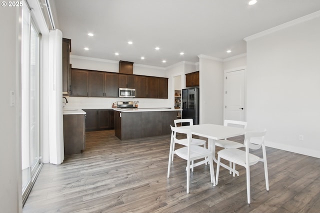 29169 NW King St, North Plains, OR 97133 - kitchen featuring crown molding, dark brown cabinetry, appliances with stainless steel finishes, light wood-style floors, and a kitchen island
