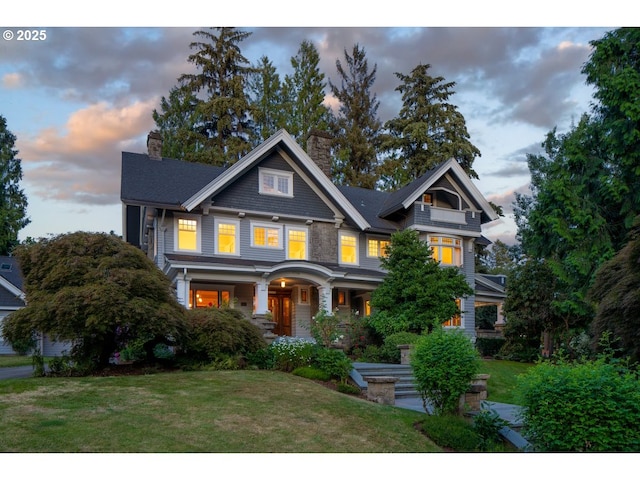 craftsman house with a chimney, a front yard, and a porch
