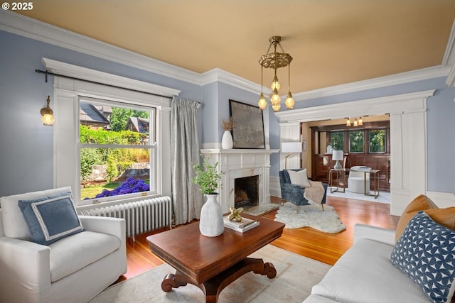 1314 SE 55th Ave, Portland, OR 97215 - living area with radiator heating unit, a chandelier, ornamental molding, wood finished floors, and a high end fireplace