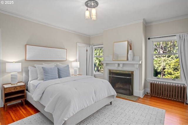1314 SE 55th Ave, Portland, OR 97215 - bedroom featuring radiator, wood finished floors, crown molding, a fireplace with flush hearth, and baseboards