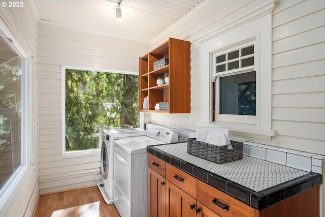 1314 SE 55th Ave, Portland, OR 97215 - washroom with light wood finished floors, washing machine and dryer, wooden walls, healthy amount of natural light, and cabinet space