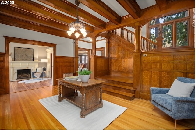 1314 SE 55th Ave, Portland, OR 97215 - living room with ornate columns, beamed ceiling, wood walls, a fireplace, and light wood-type flooring
