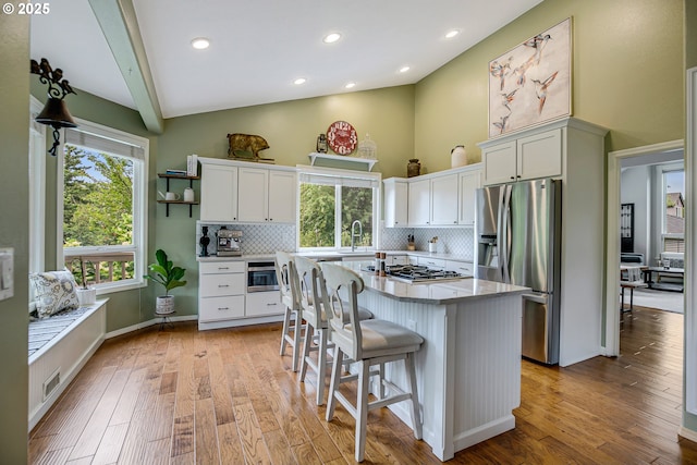 11942 SE Sunny Way, Happy Valley, OR 97086 - kitchen featuring stainless steel appliances, high vaulted ceiling, backsplash, a breakfast bar area, and white cabinetry