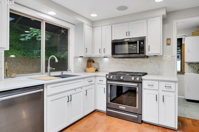 2002 Kimberly Dr, Eugene, OR 97405 - kitchen featuring appliances with stainless steel finishes, a sink, light countertops, light wood-type flooring, and white cabinets