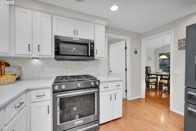 2002 Kimberly Dr, Eugene, OR 97405 - kitchen featuring stainless steel gas range, light wood-type flooring, white cabinets, tasteful backsplash, and recessed lighting