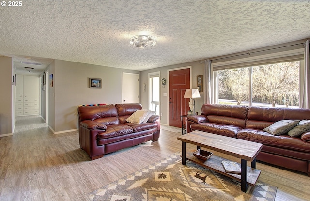 living area with baseboards, a textured ceiling, and wood finished floors