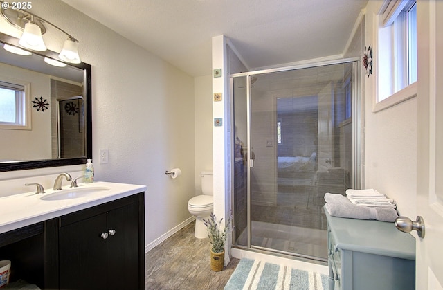 full bathroom with toilet, wood finished floors, a shower stall, baseboards, and vanity