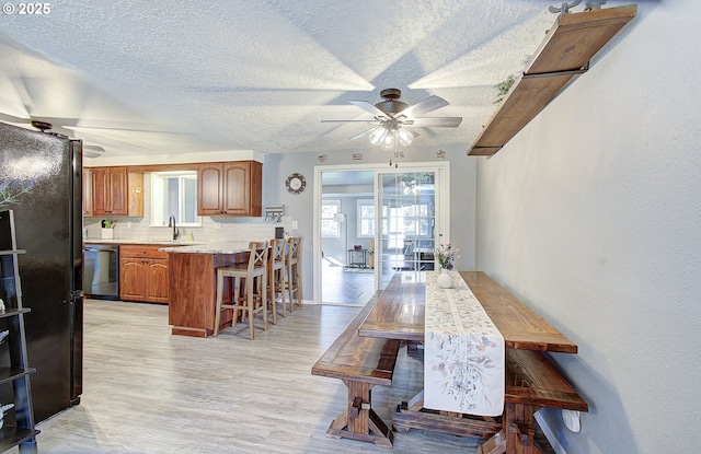 dining space featuring plenty of natural light, a ceiling fan, light wood-type flooring, and a textured ceiling