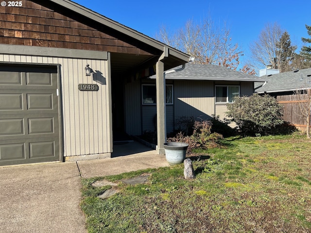 view of exterior entry with a garage and a lawn