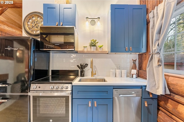 kitchen with tasteful backsplash, appliances with stainless steel finishes, sink, and blue cabinets