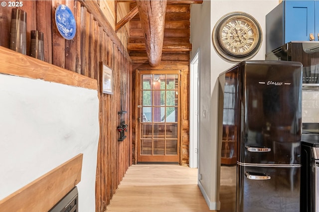 doorway featuring beamed ceiling and light wood-type flooring