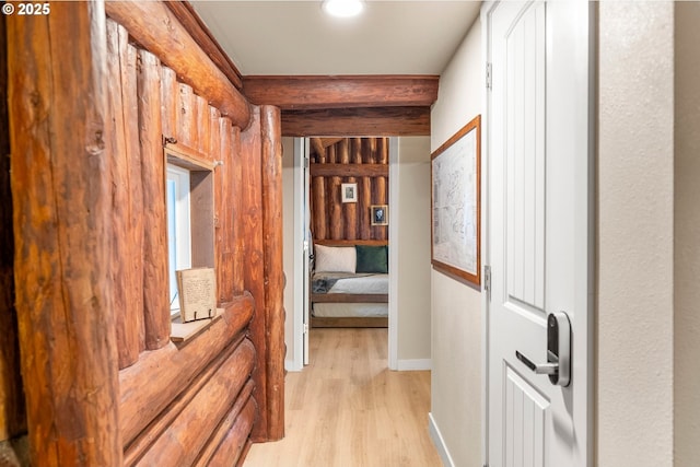 hallway featuring beamed ceiling and light hardwood / wood-style floors