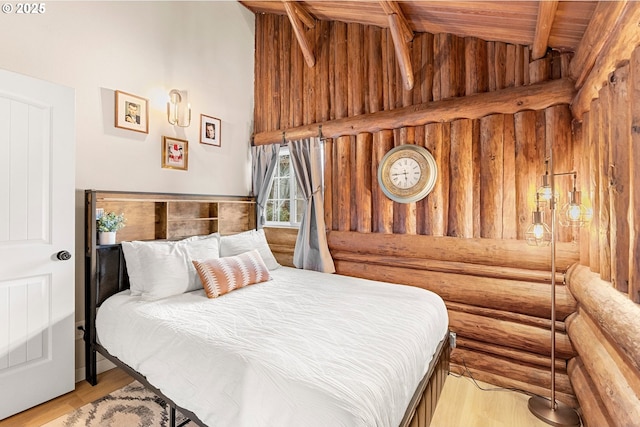 bedroom with rustic walls, high vaulted ceiling, light hardwood / wood-style floors, wooden ceiling, and beamed ceiling