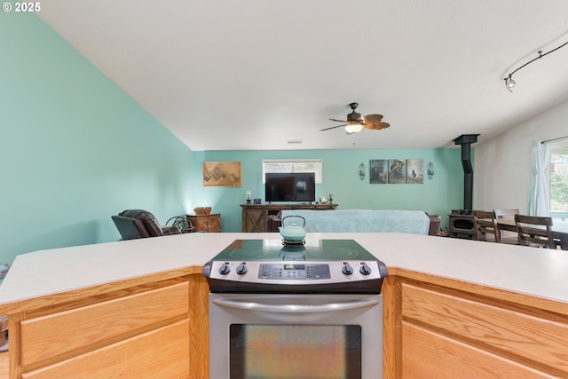 kitchen featuring a ceiling fan, electric stove, open floor plan, light countertops, and a wood stove