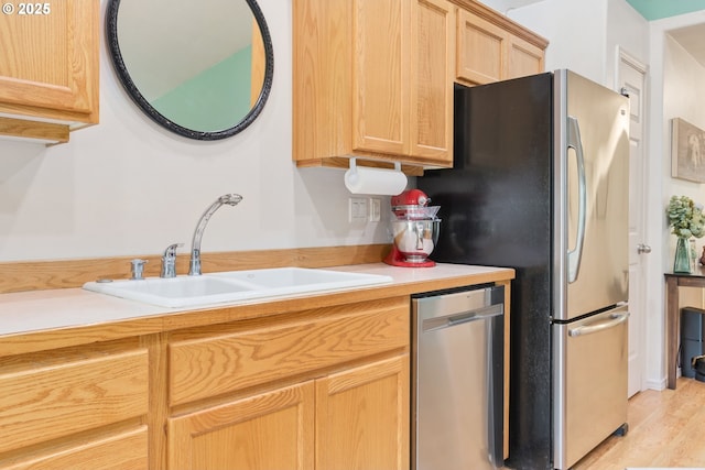 kitchen featuring light wood-style flooring, stainless steel appliances, light brown cabinetry, light countertops, and a sink