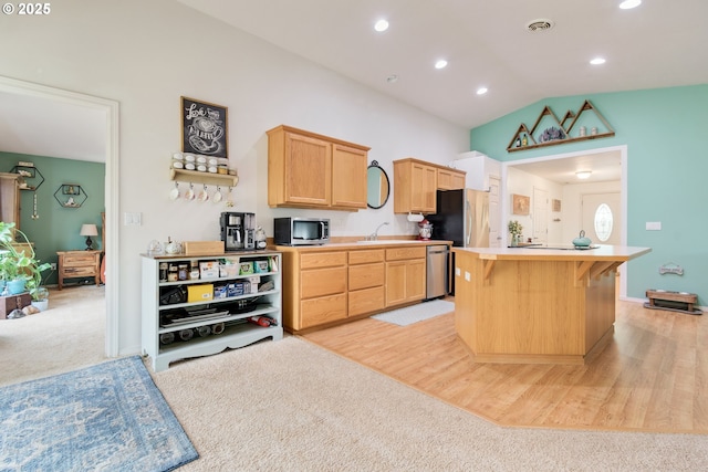 kitchen with light brown cabinetry, a sink, appliances with stainless steel finishes, light countertops, and vaulted ceiling