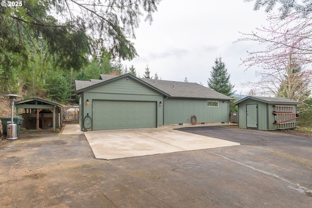 exterior space with a shingled roof, crawl space, concrete driveway, a garage, and an outbuilding