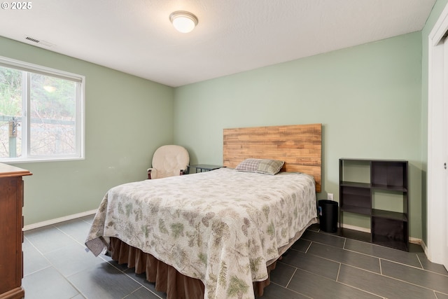 bedroom featuring dark tile patterned floors, visible vents, and baseboards