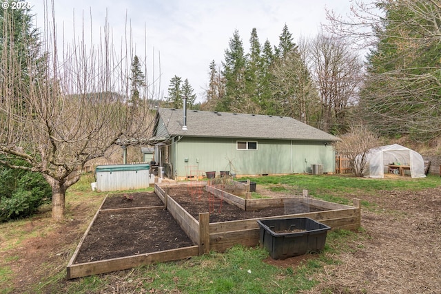 rear view of house featuring an outbuilding, a vegetable garden, a greenhouse, and central AC unit