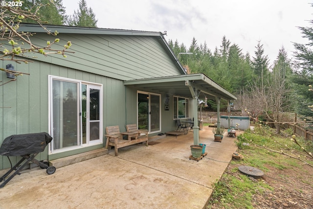 back of property featuring a jacuzzi, a patio, and fence