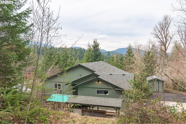 exterior space with a mountain view and a shingled roof