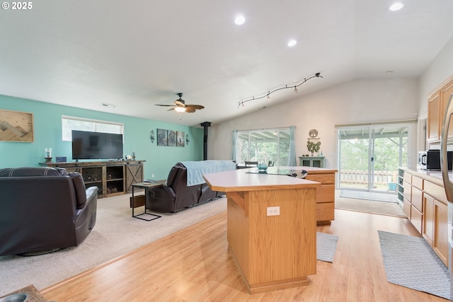 kitchen featuring a center island, open floor plan, light countertops, vaulted ceiling, and a wood stove