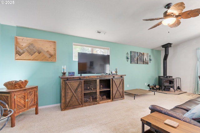 carpeted living area with visible vents, baseboards, ceiling fan, and a wood stove