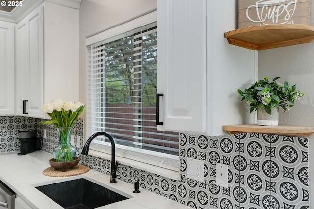 room details with white cabinets, open shelves, a sink, backsplash, and light stone counters