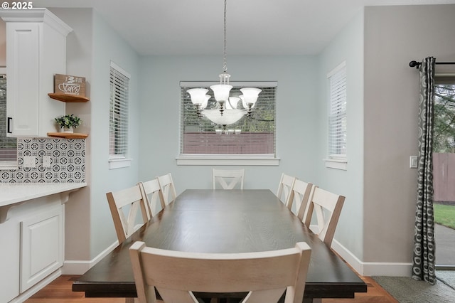 dining area featuring a notable chandelier, baseboards, and wood finished floors