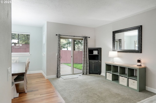 doorway with baseboards, a textured ceiling, and wood finished floors