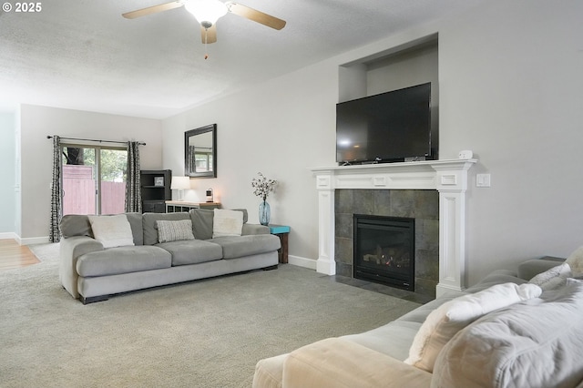 carpeted living room with baseboards, a ceiling fan, and a tile fireplace