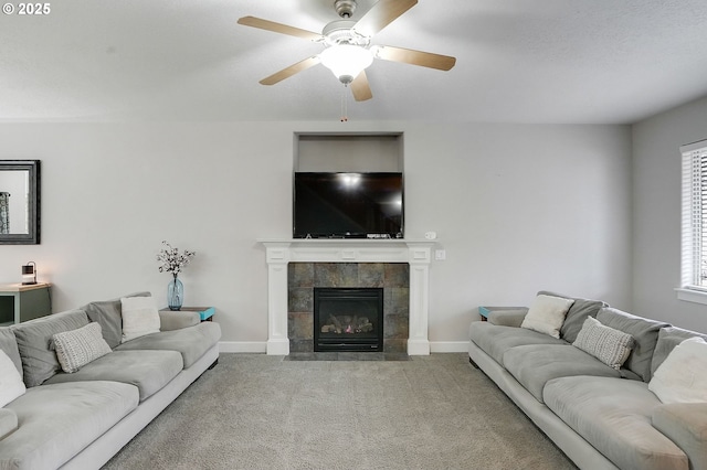 living area with carpet, a tile fireplace, baseboards, and a ceiling fan