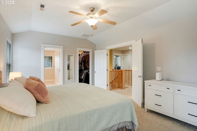 bedroom with visible vents, a closet, a spacious closet, vaulted ceiling, and light colored carpet