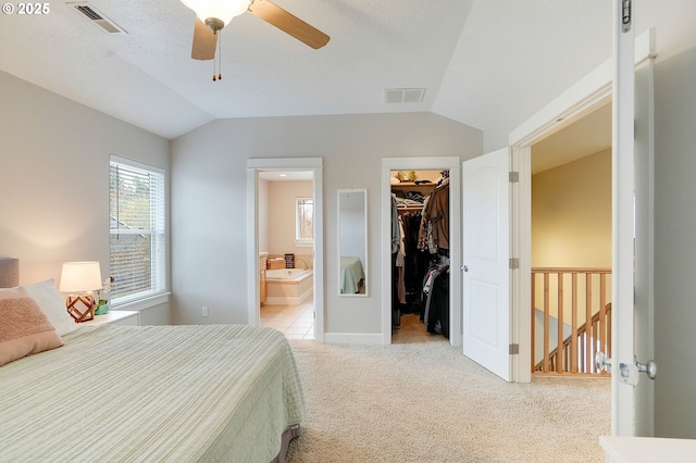 bedroom featuring a closet, visible vents, light carpet, a walk in closet, and lofted ceiling