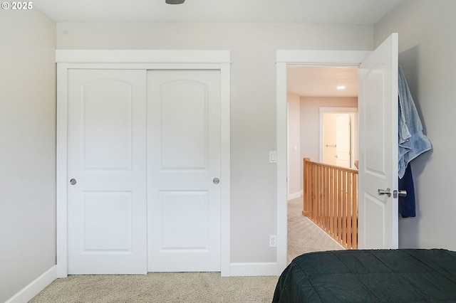 carpeted bedroom with a closet and baseboards