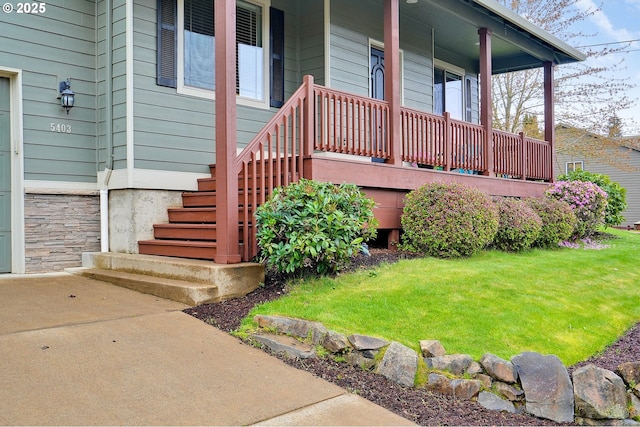 entrance to property with a porch and a lawn