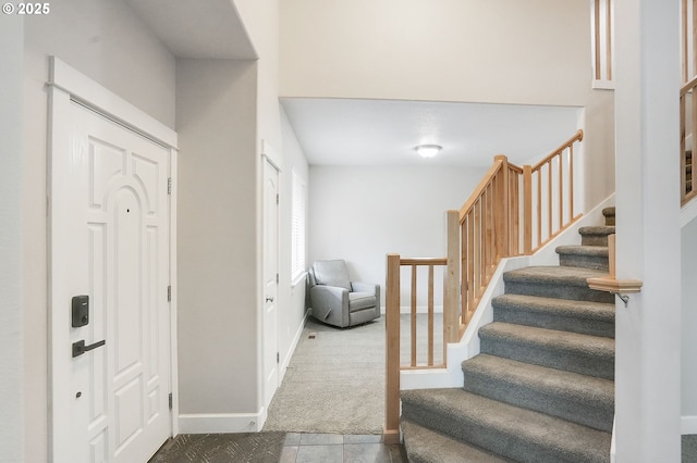 entrance foyer featuring baseboards, carpet, and stairway
