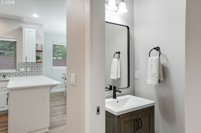 bathroom featuring decorative backsplash, recessed lighting, vanity, and wood finished floors