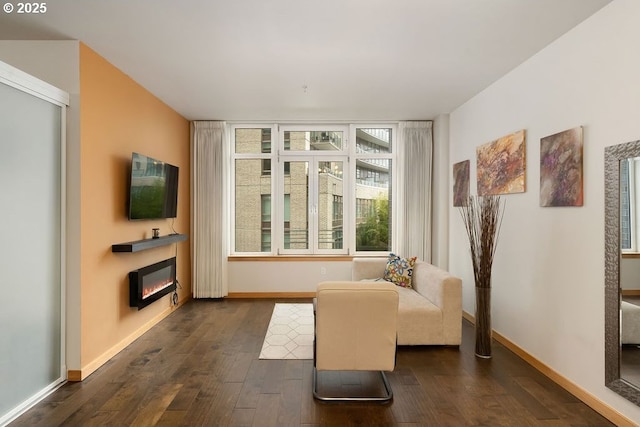 living area with baseboards, dark wood finished floors, and a glass covered fireplace