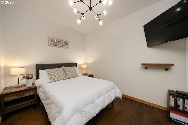 bedroom with baseboards, a notable chandelier, and wood finished floors