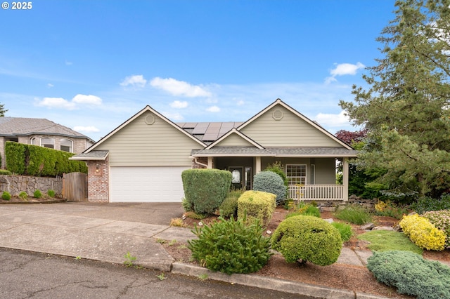 15745 SE Bybee Dr, Portland, OR 97236 - view of front facade with a porch, concrete driveway, an attached garage, roof mounted solar panels, and roof with shingles