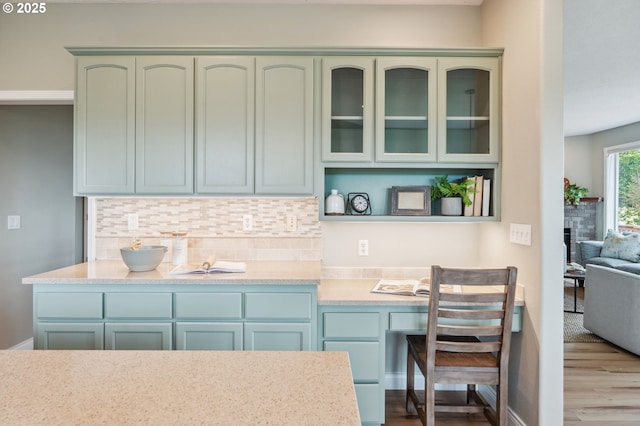 15745 SE Bybee Dr, Portland, OR 97236 - kitchen featuring green cabinets, wood finished floors, decorative backsplash, and a stone fireplace