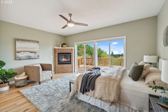 15745 SE Bybee Dr, Portland, OR 97236 - bedroom featuring access to outside, wood finished floors, a tile fireplace, ceiling fan, and baseboards