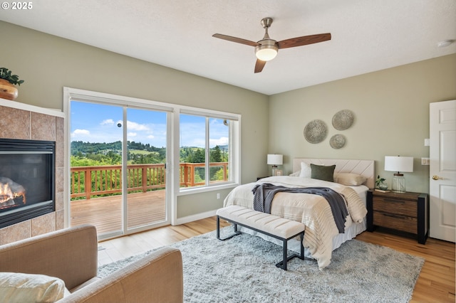15745 SE Bybee Dr, Portland, OR 97236 - bedroom with access to outside, light wood finished floors, a fireplace, baseboards, and a ceiling fan
