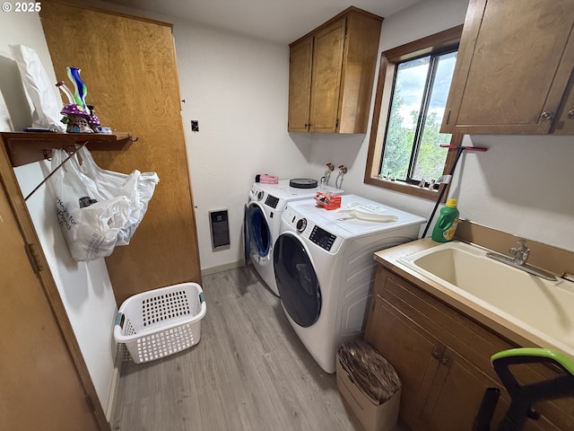laundry room featuring washer and dryer, cabinet space, light wood-style flooring, and baseboards