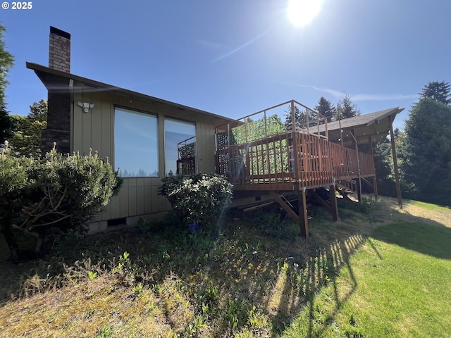 rear view of house featuring a chimney, a yard, and a wooden deck