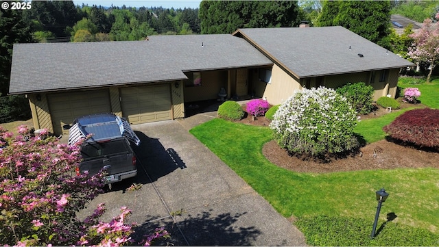 ranch-style house featuring a front yard, roof with shingles, a garage, and driveway