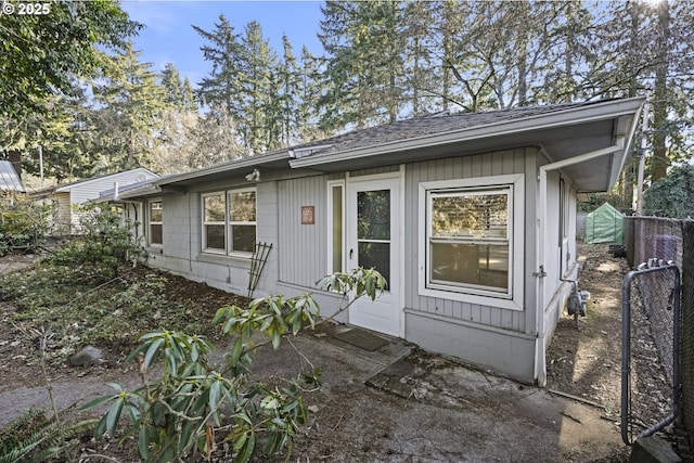 exterior space featuring roof with shingles and fence